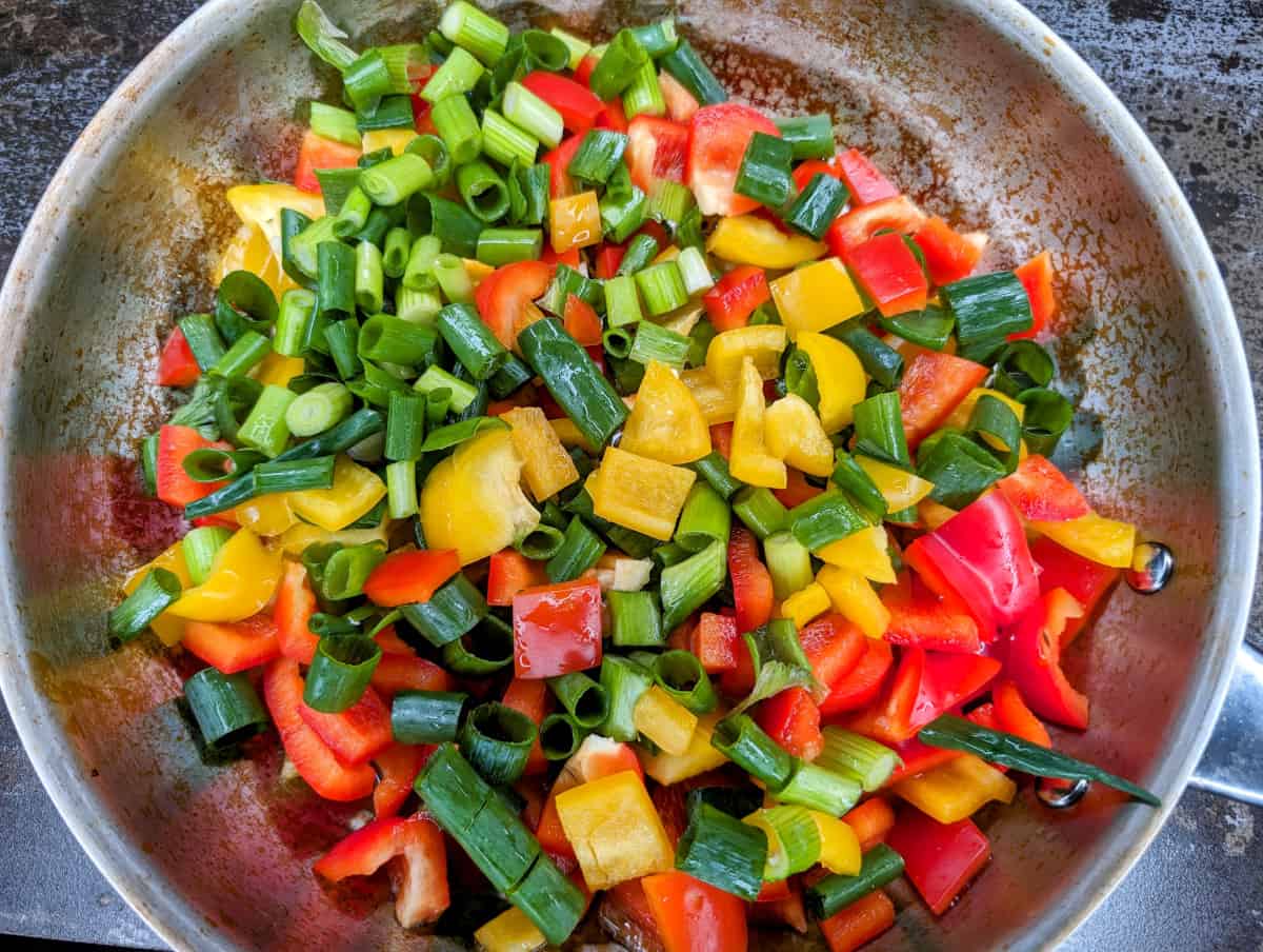 Tofu scramble in pan with raw vegetables.