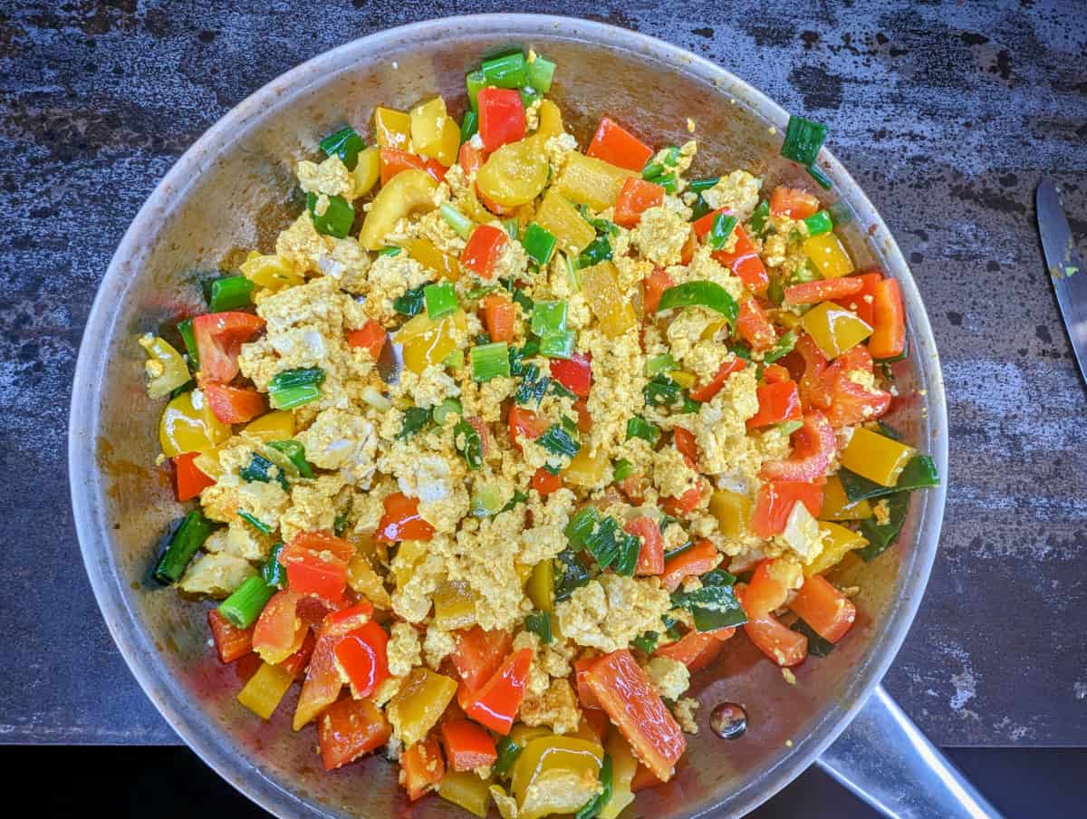 Tofu scramble in pan with sauteed vegetables.