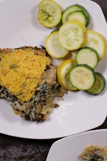 cheese, leek, and artichoke pie plated with green and yellow summer squash