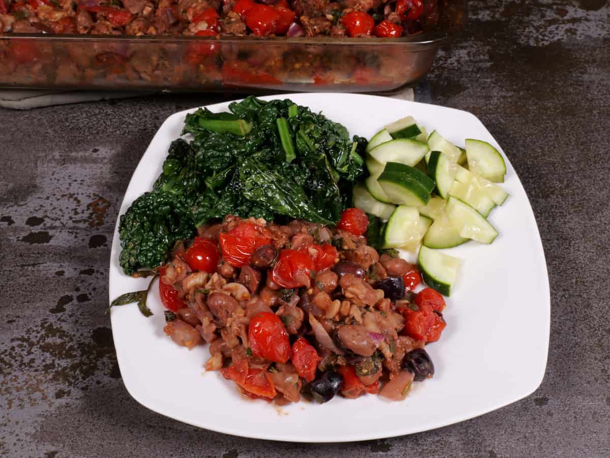 plated bean, bread, and tomato casserole with lacinato kale and cucumbers in vinegar