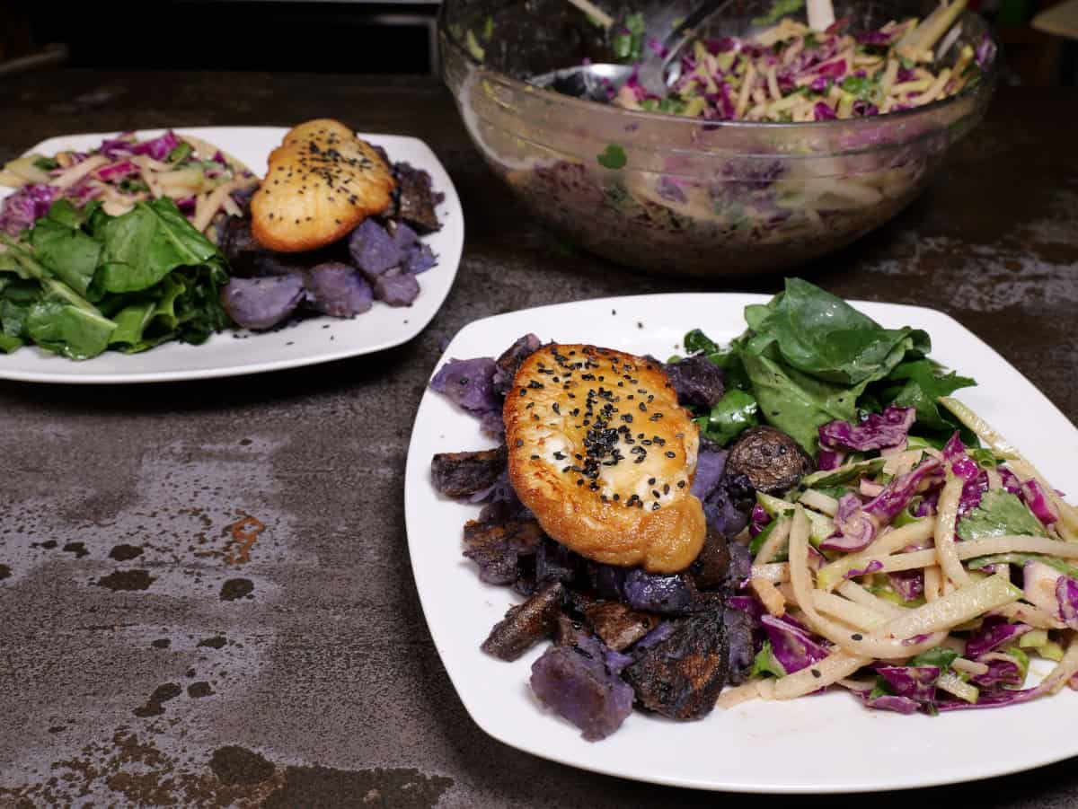 The asian slaw with almond dressing as a side on a dish of purple potatoes and Lion's Mane mushrooms.