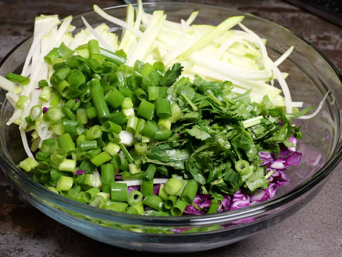 Placing the cilantro and scallions into the salad.
